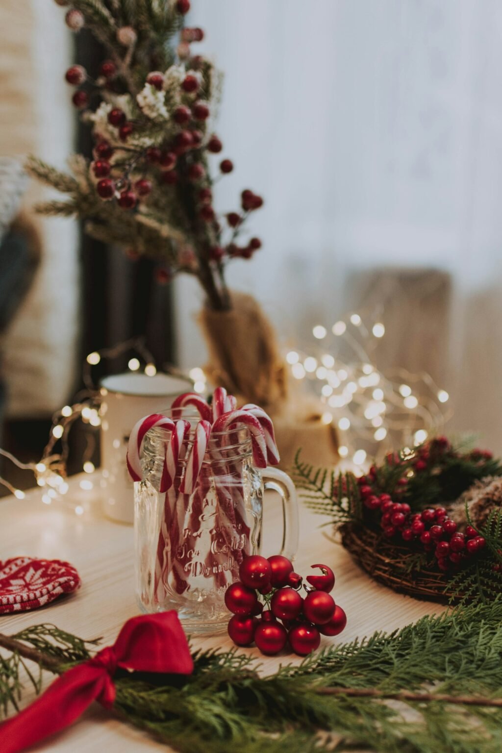 Candy canes in a glass jar with red ornaments