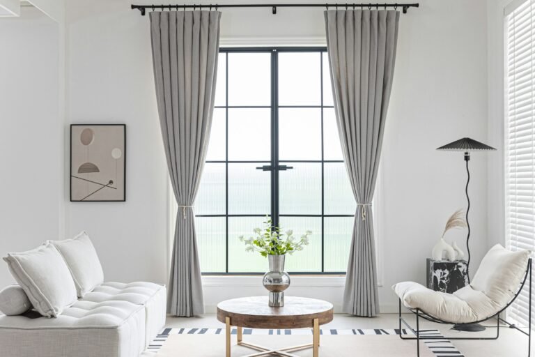 Thermal insulated curtains in soft grey framing a tall living room window