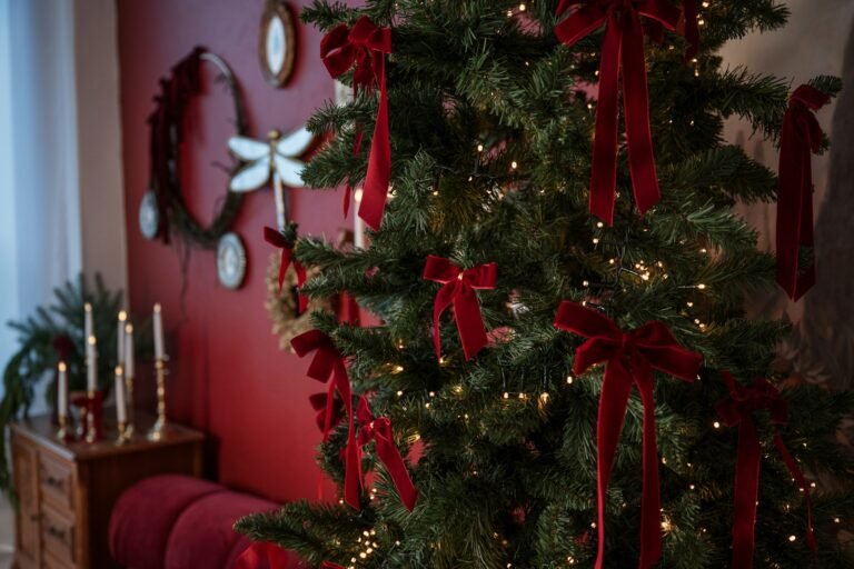 Velvet Christmas bows in deep red tied all over a lit artificial tree in a cozy red living room