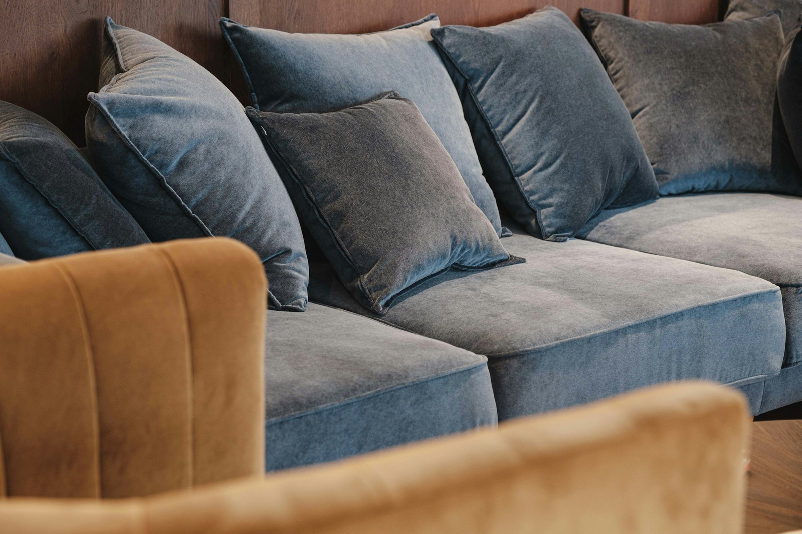 Velvet pillow covers in soft blue tones stacked on a plush velvet sofa