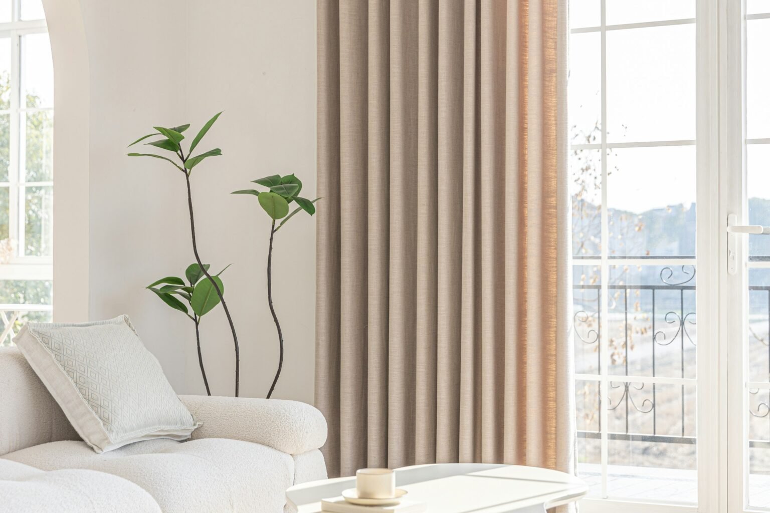 White linen curtains in a warm natural tone beside a bright living room window