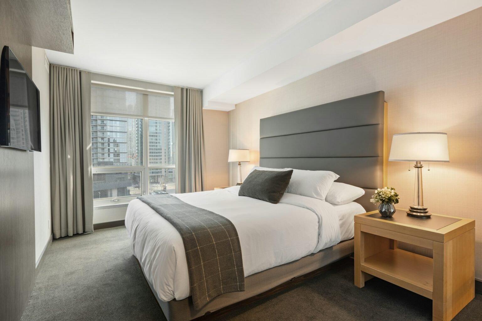 How to make your bedroom smell like a hotel: a crisp white hotel-style bed with gray throw and bedside lamps