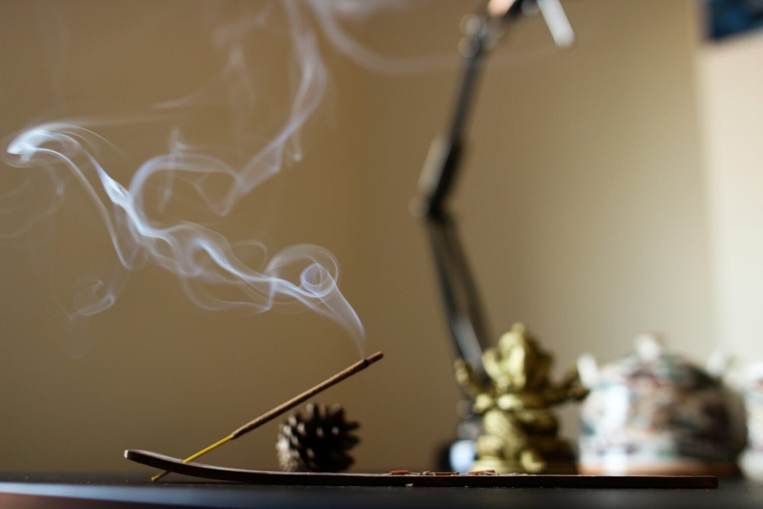 Wooden incense holder idea: a lit incense stick and smoke on a calm home desk