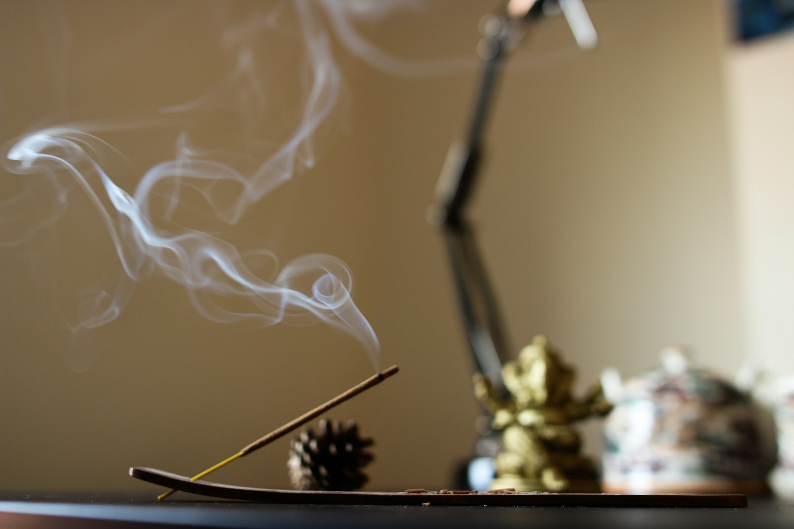 Wooden incense holder idea: a lit incense stick and smoke on a calm home desk