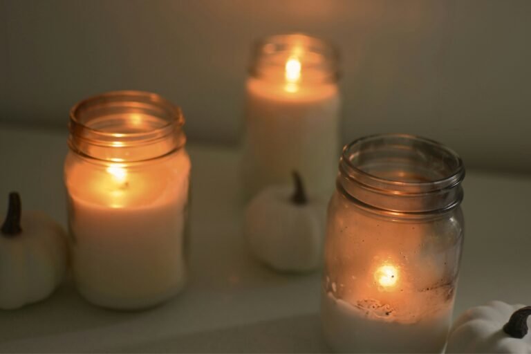 Spiced pumpkin candle mood: glowing jar candles on a soft, cozy fall table